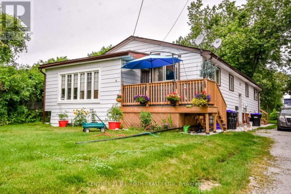 Front view of the white house with a bay window, deck, and grassy lawn. - 6 Caroline Street, Ramara