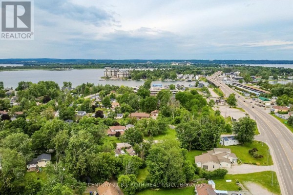Aerial view showing the property nestled among trees with a distant body of water. - 6 Caroline Street, Ramara