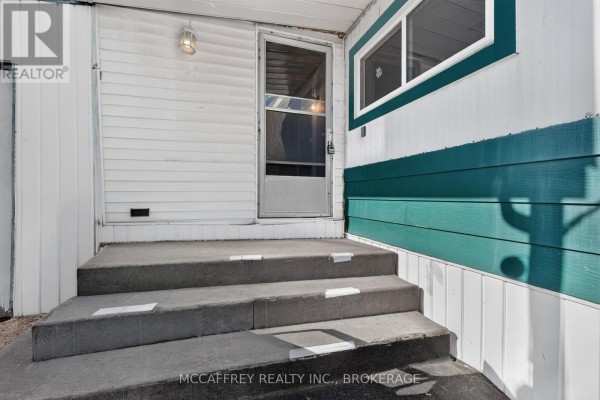 Close-up view of the front entrance stairs and door of a white mobile home. - 6 Cedar Street, Greater Napanee