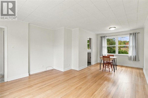 Living and dining area with light wood floors, white walls, and a table with two chairs. - 6 Cherry Hill Road, St  John S