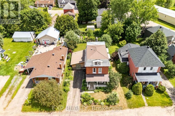 Aerial view of 6 Crawford Street, a red brick house with a mansard roof, surrounded by other homes and trees. - 6 Crawford Street, Whitewater Region
