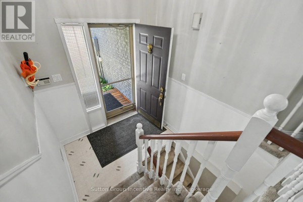 View looking down into the entryway with a dark brown front door and white staircase. - 6 Donald Crescent, Wasaga Beach
