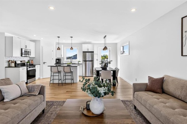 Open-concept living, dining, and kitchen area with hardwood floors, white cabinets, and stainless steel appliances. - 6 Falcon Bay, Ste Anne