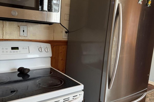 Kitchen detail showing a white electric stove, stainless steel refrigerator, and microwave. - 6 Glen Avenue, St  Catharines