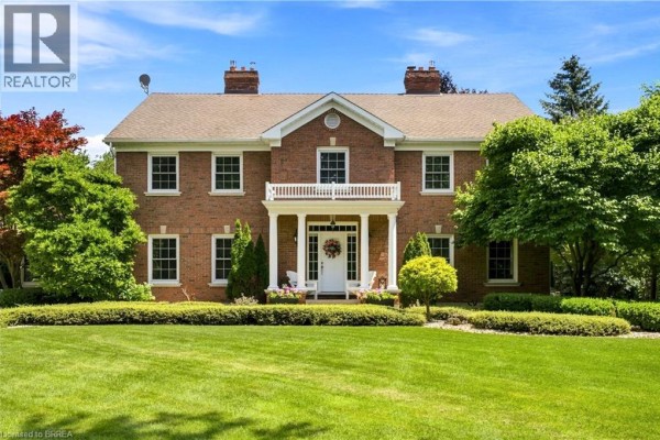 Front view of a two-story red brick house with a white portico and manicured lawn. - 6 Hickory Hollow, Brant County