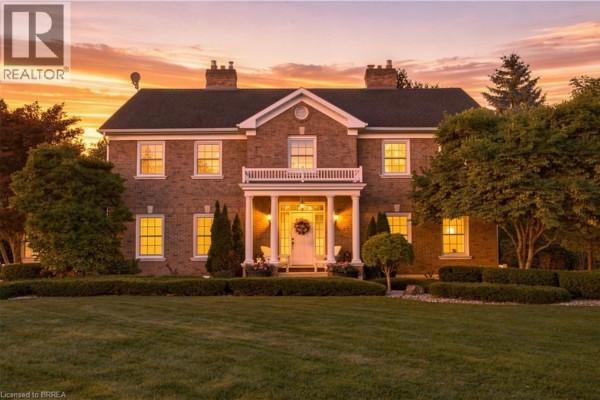 Front facade of a brick house at sunset with illuminated windows and a dramatic sky. - 6 Hickory Hollow, Brant County
