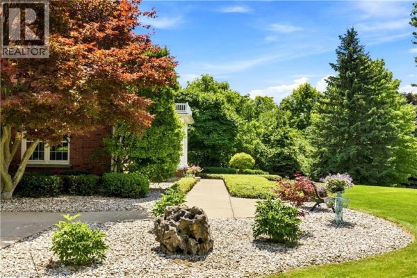 Pathway leading to the house through a landscaped garden with decorative rocks and trees. - 6 Hickory Hollow, Brant County