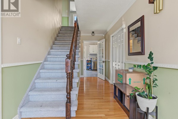 Interior hallway with hardwood floors, carpeted stairs, and doors leading to kitchen and living areas. - 6 Kilkenny Street, St  John S