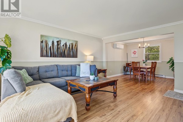 Open concept living and dining room with a large sectional sofa, coffee table, and wooden dining set. - 6 Kilkenny Street, St  John S