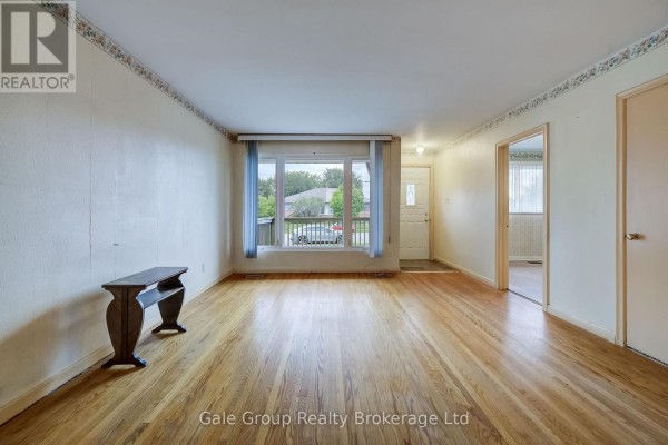 View of the living room showing hardwood floors, a large window, and interior doors. - 6 Langstone Crescent, Halton Hills