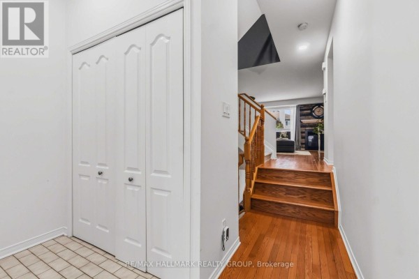 Interior view of a hallway with beige tile flooring, white bi-fold doors, and wooden stairs leading up. - 6 Maravista Drive, Ottawa