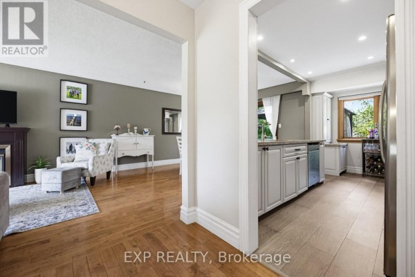 View from hallway into living room with fireplace and kitchen with grey cabinets. - 6 Palace Street, Caledon