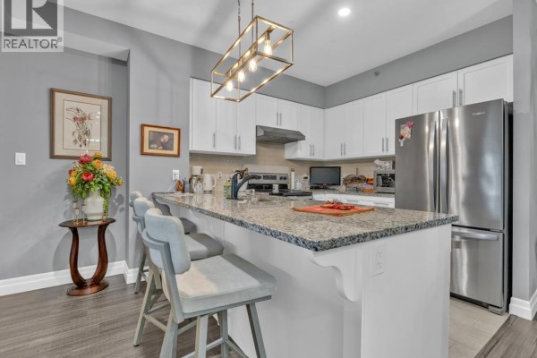 Bathroom with a white tub, toilet, and vanity with a granite countertop and mirror. - 6 Park Unit# 205, Kingsville