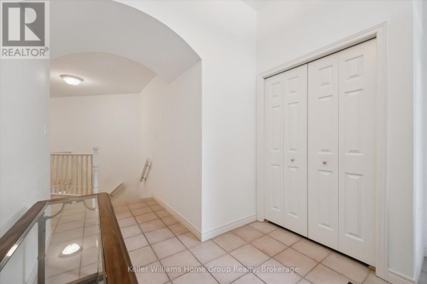 Hallway with tiled flooring, a wooden banister railing, and double cream-colored doors on the right. - 6 Parkside Drive, Guelph