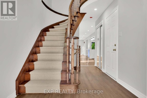 Interior view of a home entrance with a glass-paneled black door and a wooden staircase. - 6 Purdy Crescent W, Toronto