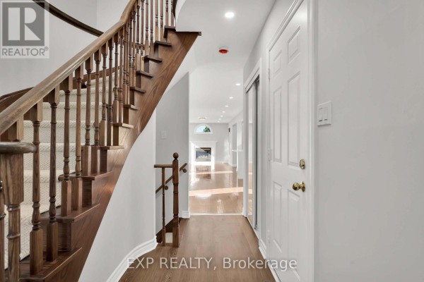 Interior view of a spacious foyer with a curved wooden staircase and hardwood floors. - 6 Purdy Crescent W, Toronto