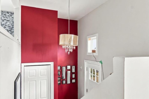Interior view of a staircase with a red accent wall, white doors, and a chandelier. - 6 Simcoe Drive, Mount Pearl