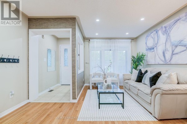 Living room with beige sofa, glass coffee table, and light wood flooring. - 6 Tansley Crescent, Ajax