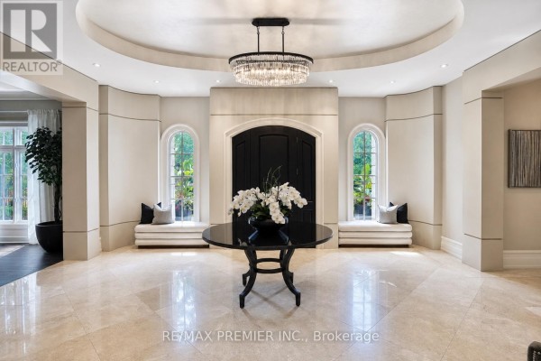 Spacious foyer with polished marble floors, a black round table, and a crystal chandelier. - 6 The Bridle Path, Toronto