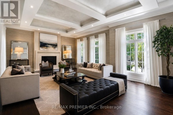 Luxurious living room with coffered ceiling, fireplace, sectional seating, and large windows with drapes. - 6 The Bridle Path, Toronto