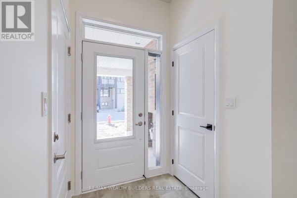 Interior entryway with white doors, wood-look flooring, and glass front door. - 6 Thornbird Crescent, Brampton