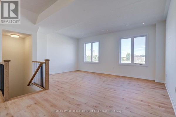 Bright living area with light wood floors, white walls, and two windows. - 6 Thornbird Crescent, Brampton
