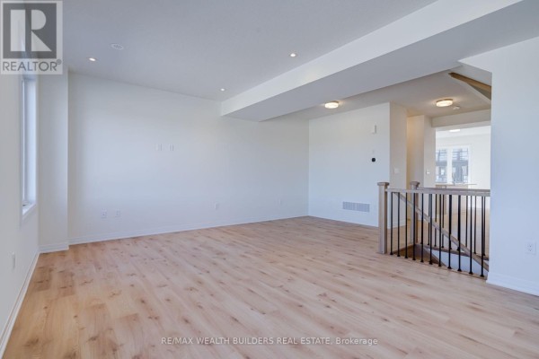 Spacious living room with light wood floors, white walls, and a staircase. - 6 Thornbird Crescent, Brampton