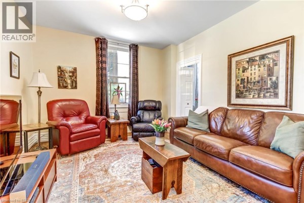Living room with brown leather sofa, red armchair, wooden coffee table, and a large framed artwork. - 6 Tolhurst Avenue, St  George