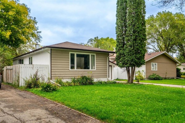 Exterior view of a beige bungalow with a white fence and a green lawn. - 6 Tulane Bay, Winnipeg