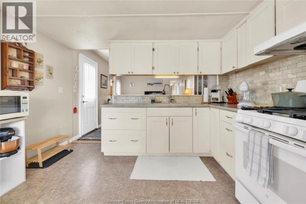 Kitchen with cream cabinets, white oven, stone tile backsplash, microwave, and a window. - 6 Viscount, Essex