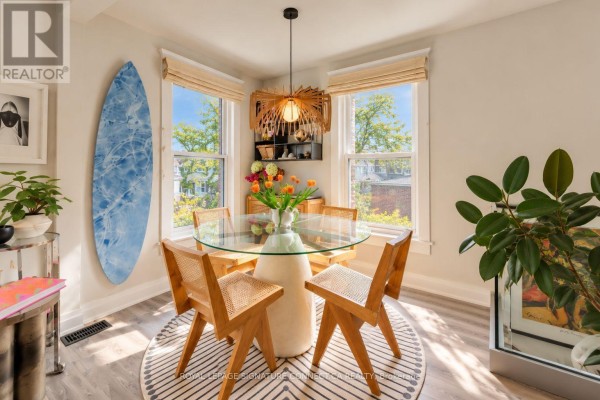 Glass-top dining table with wooden chairs near a bay window overlooking a tree-lined street. - 6 Wheeler Avenue, Toronto