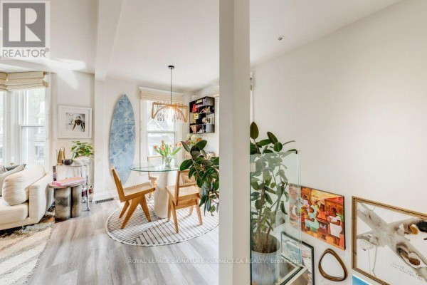Interior view showing a dining area, living room, and staircase with glass railing and artwork. - 6 Wheeler Avenue, Toronto