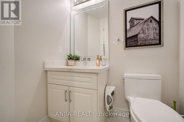 Powder room with a white vanity, mirror, toilet, and framed barn print. - 6 Wildmoor Street, Markham
