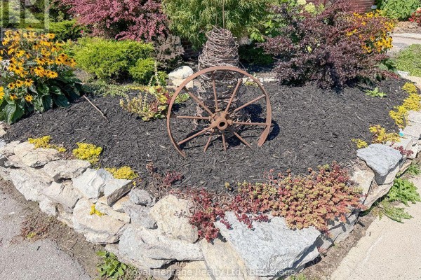 Garden bed with wagon wheel, stone wall, and flowers - 6 Willard Street Belleville