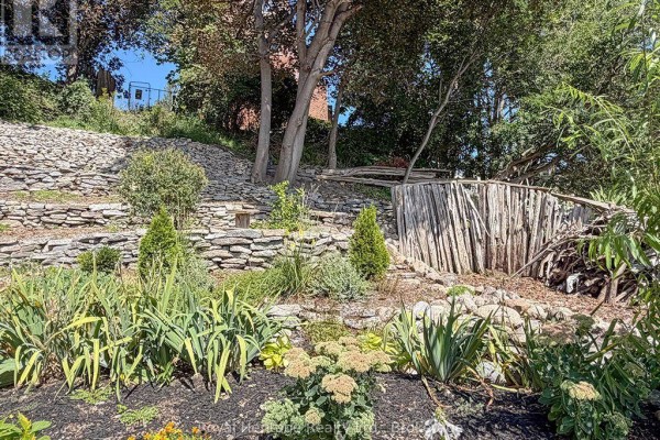 Terraced yard with stone walls, lush landscaping, and rustic wooden fence - 6 Willard Street Belleville