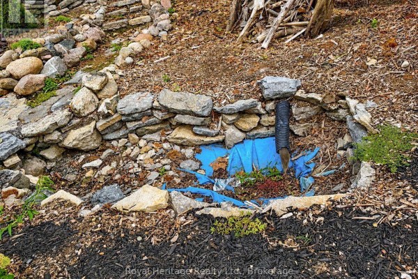 Sloped yard with stone retaining wall and drainage pipe - 6 Willard Street Belleville