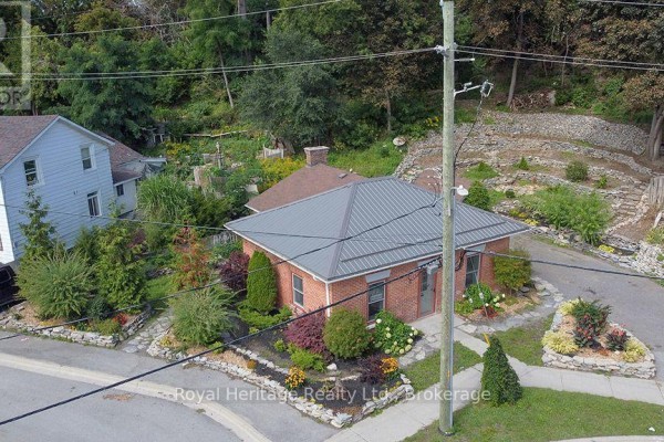 Brick house with metal roof, garden beds, stone walls, and SUV - 6 Willard Street Belleville