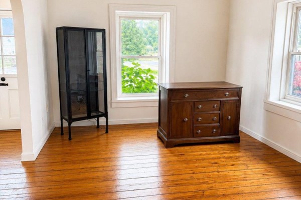 Interior room with wooden floors, two windows, a dark metal cabinet, and a wooden dresser. - 6 Willard Street, Belleville