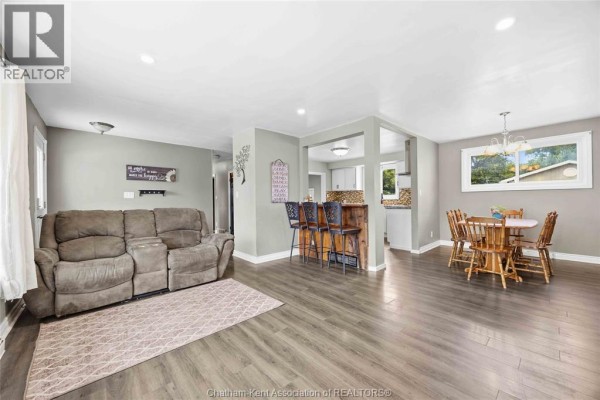 View from kitchen into open-concept living area with bar seating and chairs. - 6 York Street, Lambton Shores