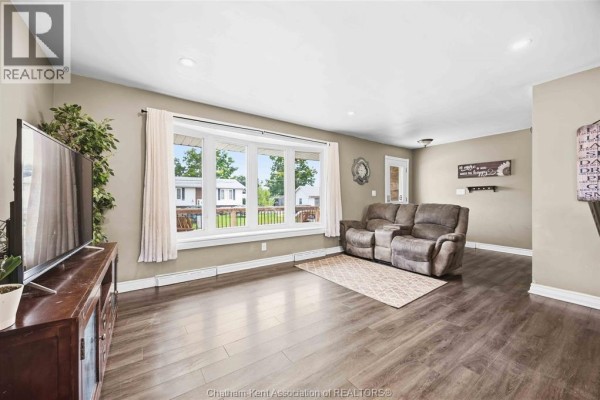 Kitchen with white cabinets, granite countertops, tiled backsplash, and stainless steel appliances. - 6 York Street, Lambton Shores