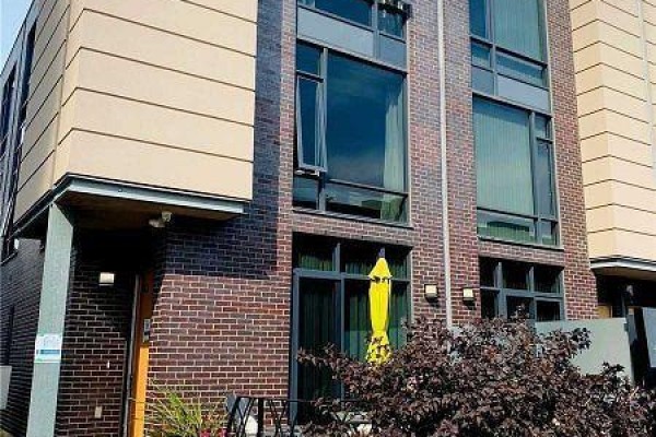 Exterior view of a red brick townhouse with large windows and a yellow umbrella on a balcony. - 60 - 27 Valhalla Inn Road, Toronto