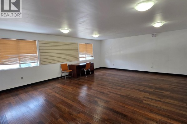 Open area with wooden floors, desk, and access to adjacent room - 60 1932 St George Avenue, Saskatoon