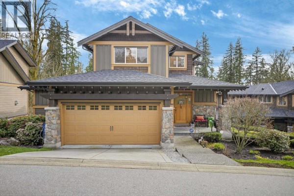 Front view of a townhouse with a brown garage door, wooden front door, and stone pillars. - 60 24185 106b Avenue, Maple Ridge