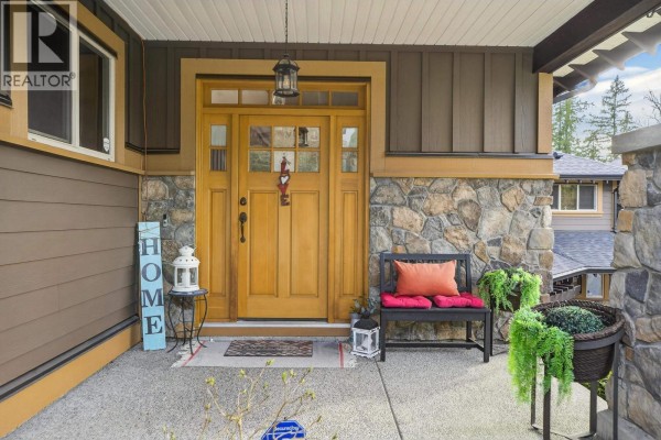 Backyard view with a green lawn, mature trees, a wooden bench, and garden beds. - 60 24185 106b Avenue, Maple Ridge