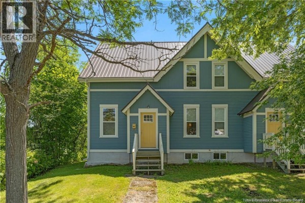 Front facade of a blue multi-family home with two identical yellow front doors. - 60-62 Queensway, St  Stephen