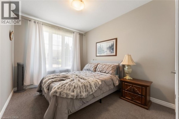 Bedroom with a queen-size bed, tan walls, carpet, and a large window. - 60 Andrew Lane, Thorold