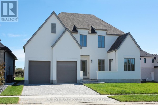 Exterior view showcasing a two-car garage and landscaped front yard. - 60 Bayshore Drive, Middlesex Centre