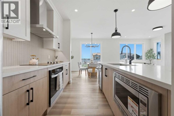 Modern kitchen with light wood cabinets, white countertops, stainless steel appliances, and a dining area view. - 60 Bridges Drive Sw, Langdon