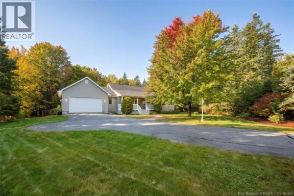 Exterior view of a home with a covered porch, attached garage, circular driveway, and autumn foliage. - 60 Eldersley Avenue, Saint John