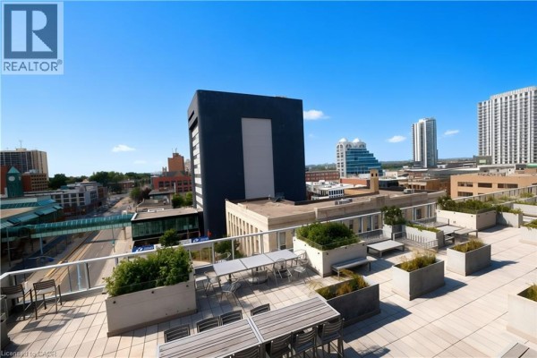 Outdoor seating and dining areas on a rooftop terrace with a panoramic view of the city. - 60 Frederick Street Unit# 1401, Kitchener